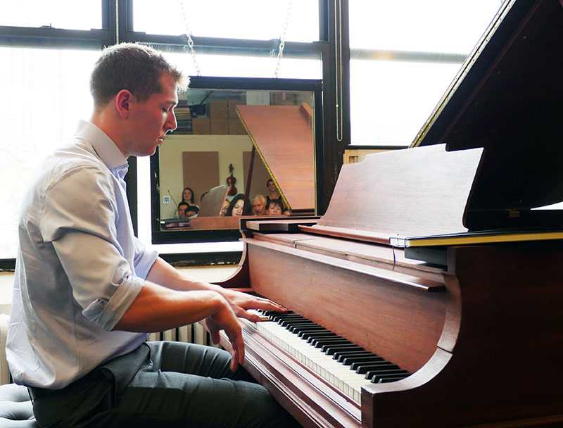 A man performing on piano at a Sage Music recital