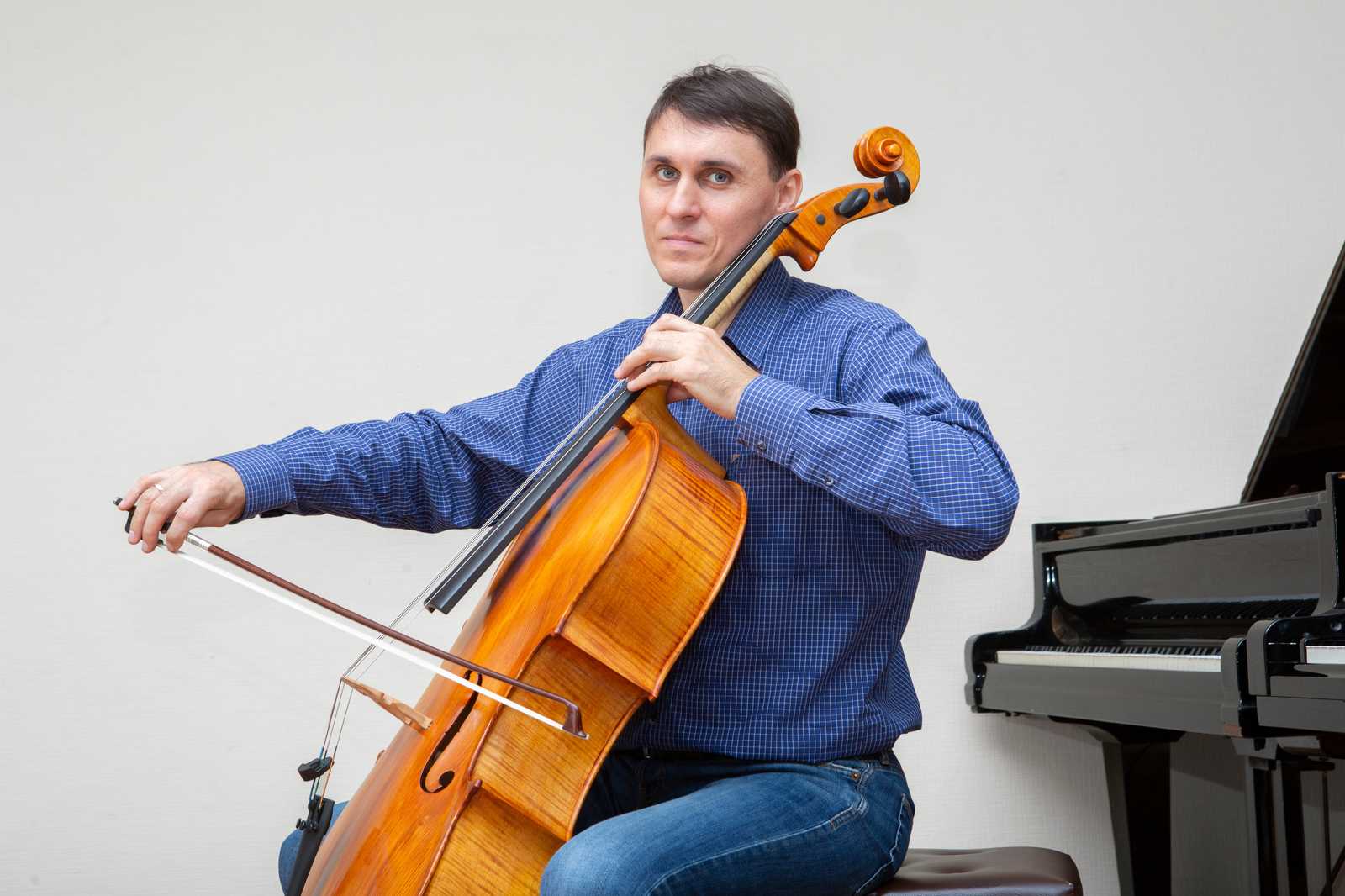 a man playing cello in front of piano