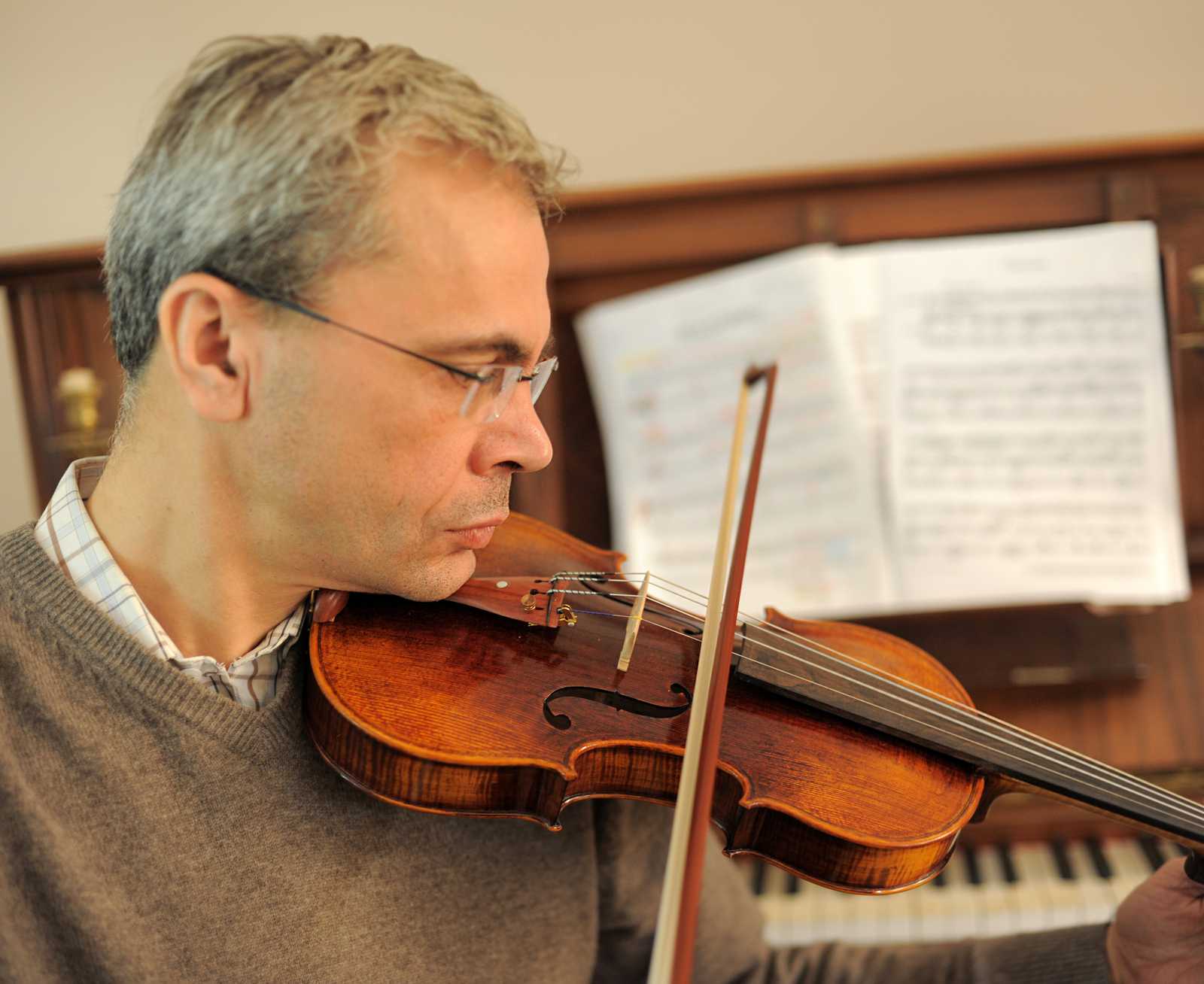 a man playing the violin in front of a piano