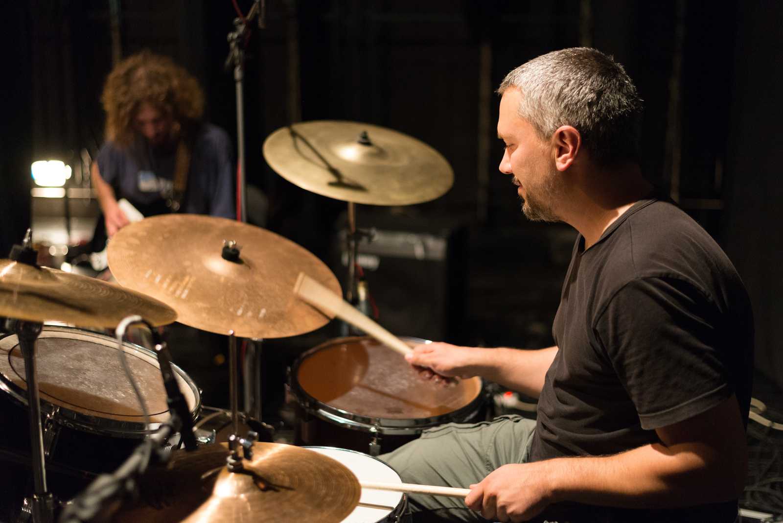 a man rehearsing on drums with a guitarist