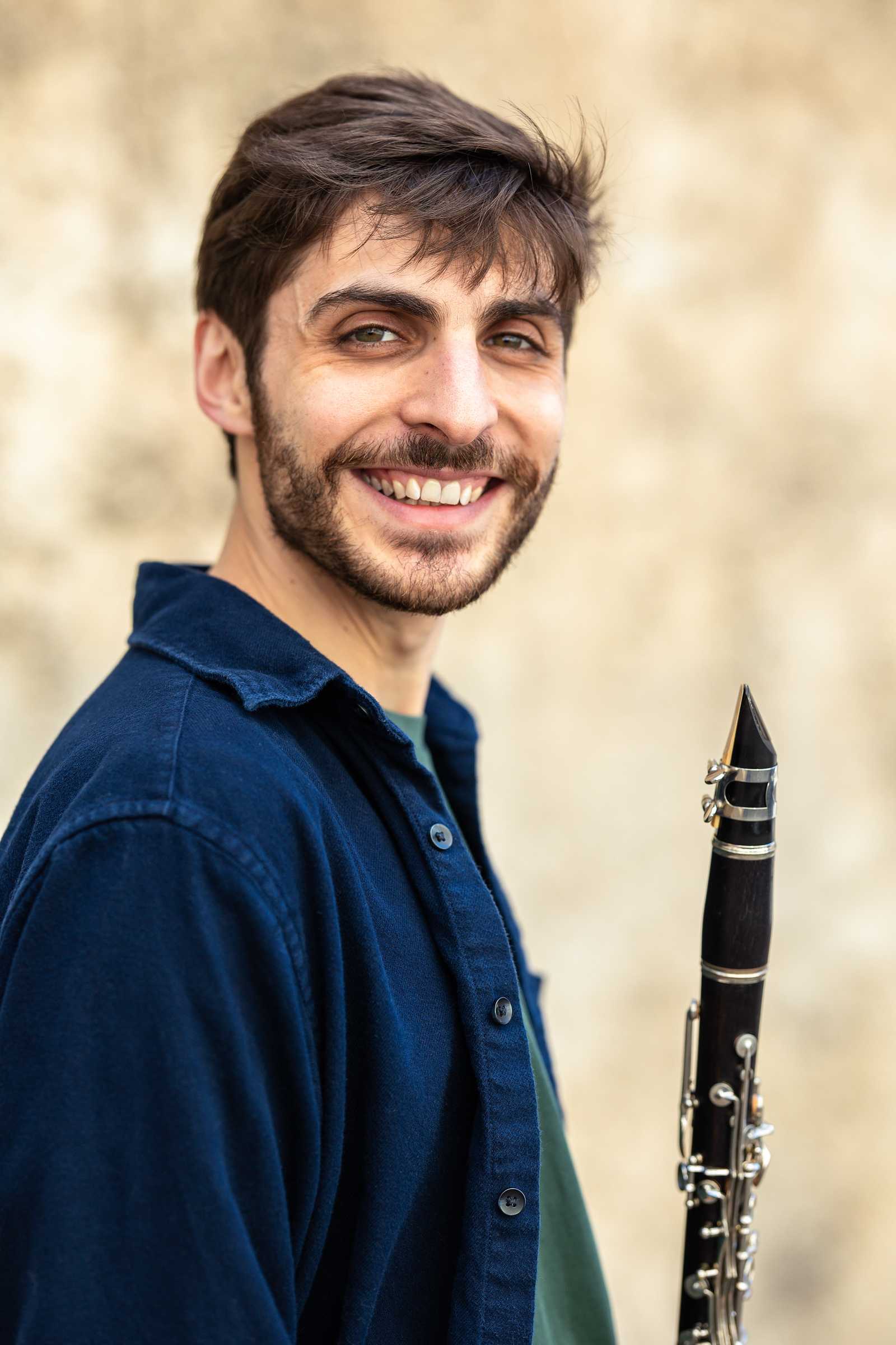 a man smiling and holding the clarinet