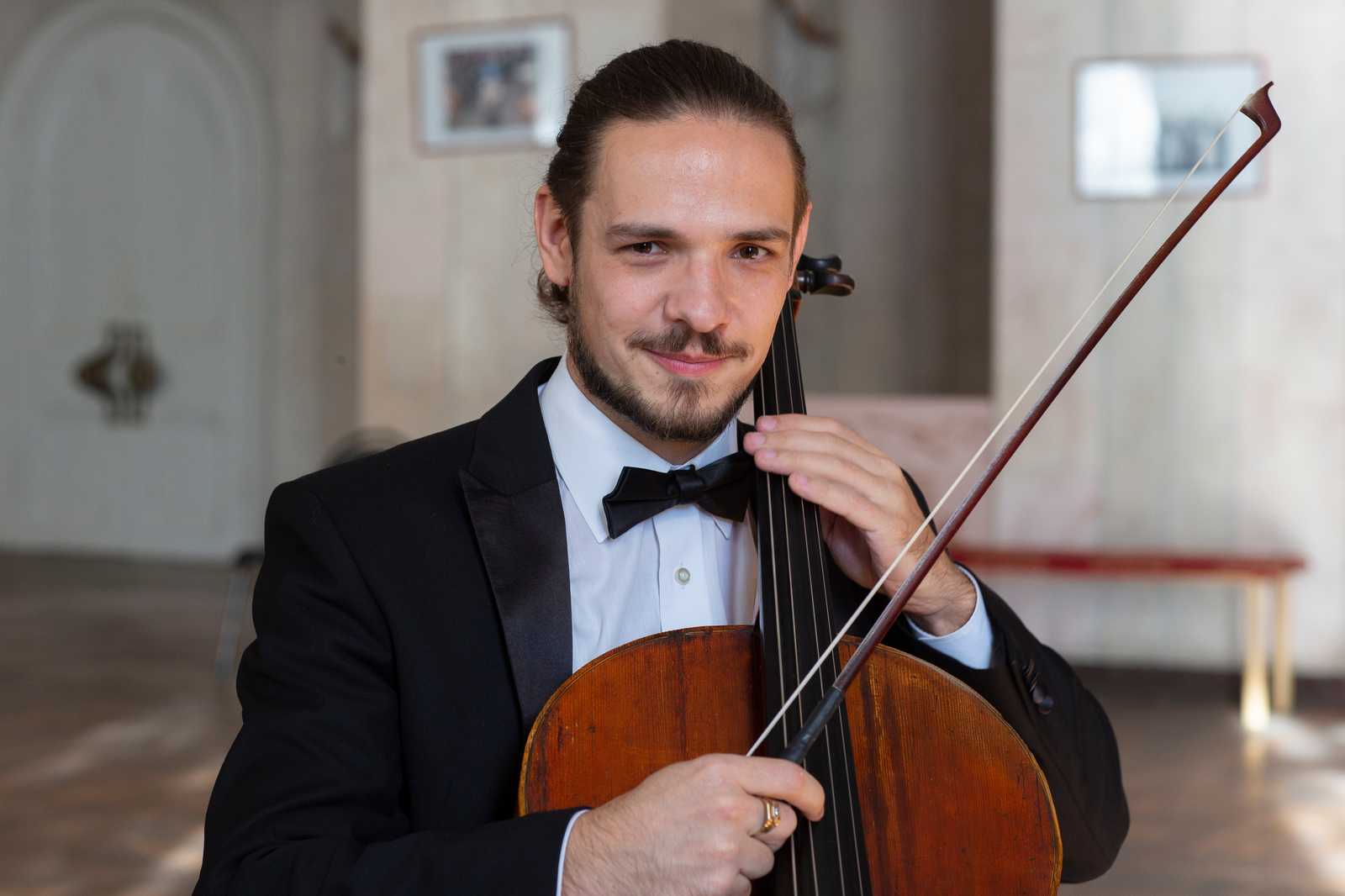 a man wearing a tuxedo holding a cello