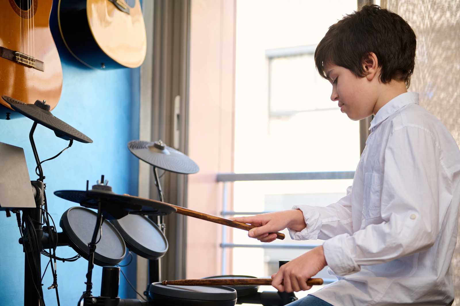 a young boy playing on an electronic drum kit
