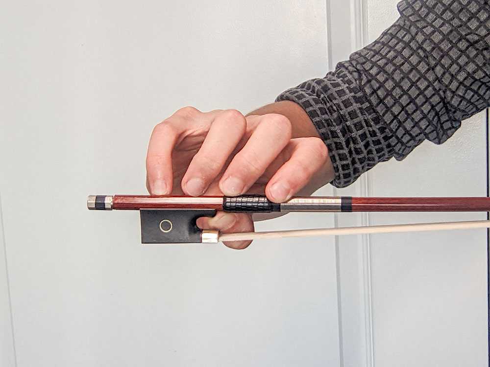 The fingers are not over the violin bow stick as they should be. This is incorrect.