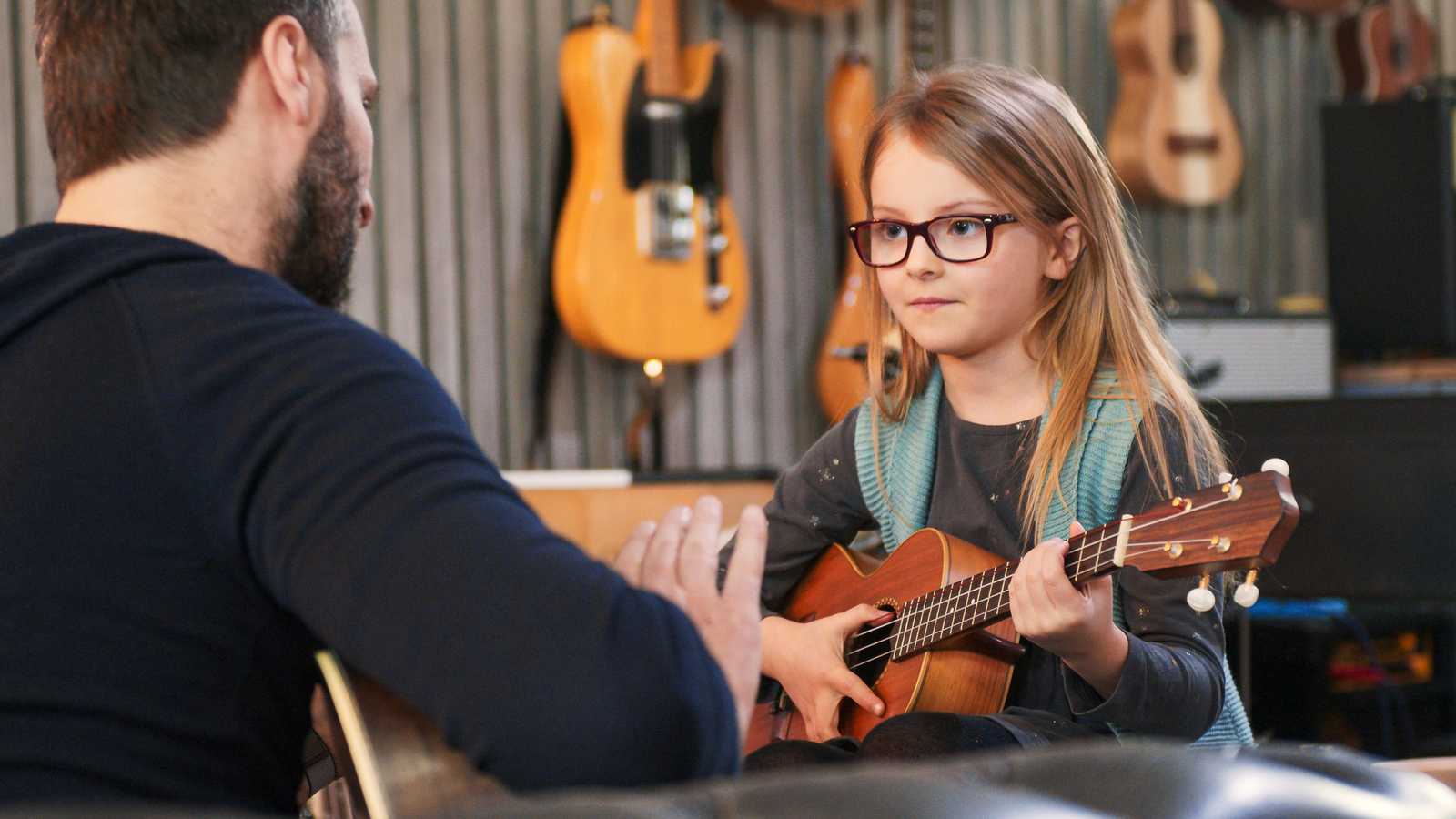 A young girld learning the ukulele
