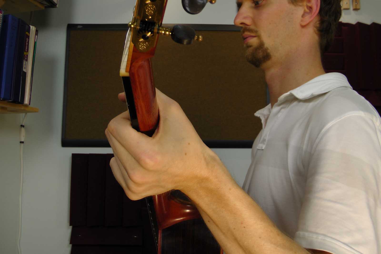 Left wrist arched on the guitar, with the thumb over the neck